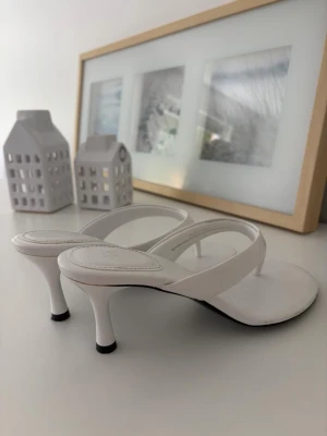 Vita sandaletter med smal klack - Snygga vita sandaletter med smal klack och breda remmar i minimalistisk design. Knappt använda, som helt nya! Slutsålda på hemsidan🫶🏼