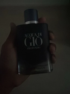 Acqua di Giò Profondo parfym - Acqua di Giò Profondo från Armani är en elegant parfym i en mörkblå, matt glasflaska med silverdetaljer och rundad form. Flaskan har en stilren design med tydlig logotyp framtill och en matchande blå kork.