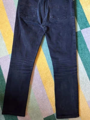 Nudie jeans slim fit - Snygga mörkblå jeans med slim passform och klassiska fem fickor. Jeansen har en enkel design utan synliga loggor och är tillverkade i ett mjukt denimtyg som känns bekvämt. Perfekta för dig som gillar ett par lite finnare byxor 27W 32L