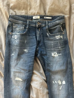 Oanvända Blå replay anbass aged jeans med slitningar  - Oanvända Blå replay anbass aged jeans med slitningar. I helt nytt skick. Riktigt schysst tvätt och snygga slitningar. Nypris runt 1800 kr 