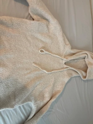 Beige fluffig hoodie från Gina Tricot - Mysig beige hoodie från Gina Tricot i storlek XS. Tillverkad i ett fluffigt, mjukt material med huva och dragsko. Perfekt för chill dagar när du vill vara både bekväm och snygg. Enkel att matcha med jeans eller mjukisbyxor.
