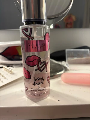 Victoria's Secret parfym - Fräsch och söt doftmist från Victoria's Secret, Sexy Angel. Flaskan är genomskinlig med rosa och svarta hjärtan och läppar som dekoration. Volymen är 250 ml och flaskan har en praktisk sprayfunktion. Perfekt för dig som gillar feminina och lekfulla dofter.