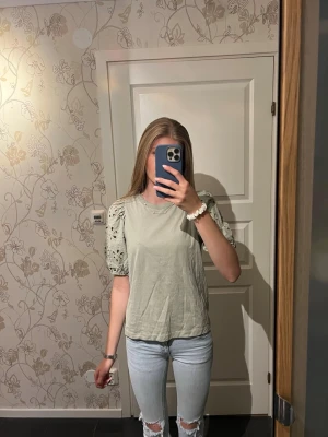 Ljusgrön topp med spetsärmar - Snygg ljusgrön topp med korta puffärmar i spets och broderade detaljer. Rak passform och rund halsringning. Perfekt för dig som vill ha en söt och trendig look. Använd två gånger så är i bra skick.
