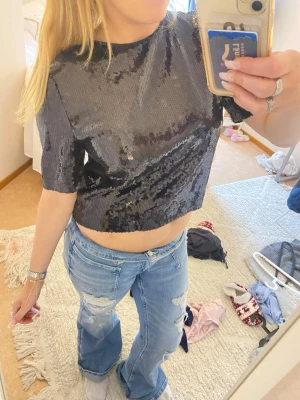 Svart glittrig croppad topp - Säljer en svart glittrig croppad topp med korta ärmar. Toppen har paljetter över hela och är perfekt för till exempel nyår eller fest använda 2 gånger så är så gott som ny🤗