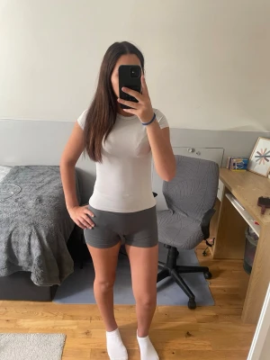 Grå tighta shorts i bomull - Säljer ett par grå tighta shorts i mjukt bomullsmaterial. De har en enkel design utan synliga detaljer och sitter midjehögt. Perfekta för en avslappnad och sportig stil.