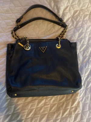 Guess väska  - Snygg svart handväska från Guess,perfekt skolväska då datorn får plats! Bra skick💕