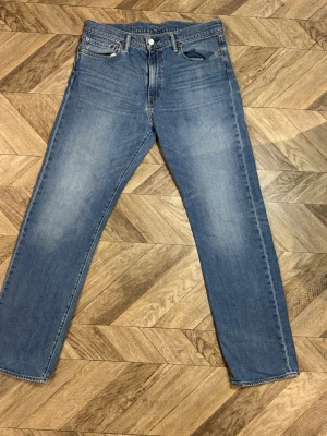 Levi's 504 - Klassiska blå jeans med rak passform och fem fickor. Jeansen har en knappgylf och subtila slitningar på framsidan för en avslappnad look. Tillverkade i denim med kontrastsömmar och bälteshällor. Perfekta för en enkel och stilren outfit. Längd 110 cm bredd 42 cm. W36 L34