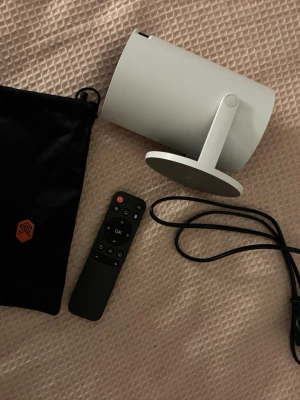 Vit Projektor med kontroll - Detta är en nästintill splitter ny projektor då den har använts endast 2 gånger. Man kan ändra bild fokus på en scroll och man kan kolla på de flesta streaming appar som på en vanlig tv. Det kommer med en kontroll och sladd för att starta projektorn.  Man kan välja till en hdmi kabel till men det kommer att kostar extra