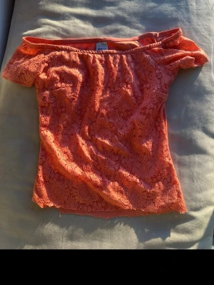Korallfärgad offshoulder topp Gina Tricot - Säljer en snygg korallfärgad offshoulder topp från Gina Tricot i spets. Toppen har korta ärmar och ett vackert spetsmönster som ger en romantisk vibe. Perfekt för dig som vill ha något extra till sommargarderoben! OBS! Toppen är alltså klippt för lite kortare passform då den va ganska lång från början. Se sista bild!🌷✌🏻 kolla gärna in mina andra fina plagg!🌷