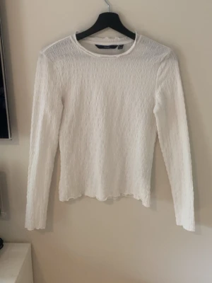 Vit långärmad topp från Vero Moda - Säljer en vit långärmad topp från Vero Moda. Toppen har en lätt strukturerad yta och rund halsringning. Passformen är normal och materialet känns mjukt och bekvämt. Perfekt att styla med jeans eller kjol för en clean look.