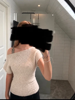 Offshoulder topp i beige från Nelly - Mysig offshoulder topp i ljusbeige från Nelly. Toppen är stickad med kort ärm och har en tight passform som framhäver figuren. Perfekt för dig som gillar en enkel men trendig look.