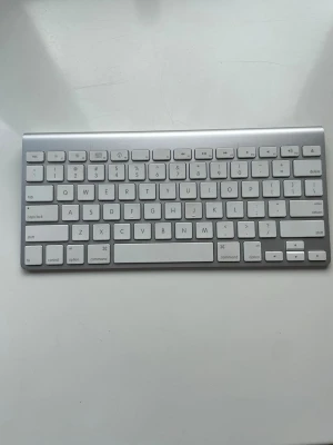 Trådlöst Apple tangentbord  - Snyggt och smidigt trådlöst apple tangentbord i aluminium med vita tangenter. Kompakt design utan numerisk del, perfekt för Mac-användare. Tangenterna är låga och har en modern look. Passar bra till både stationära och bärbara datorer.😊