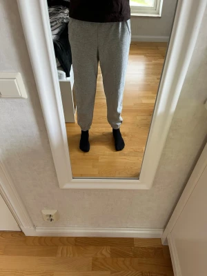 Grå mjukisbyxor med resårmidja - Säljer ett par ljusgrå mjukisbyxor med resår i midjan och benslut. Byxorna har en avslappnad passform och är fodrade med mjukt, fleeceliknande material på insidan för extra komfort. Perfekta för chill dagar hemma eller när du vill vara bekväm. Använda cirka 5 gånger, tyvärr lite för korta för mig. Nypris 299 kr.