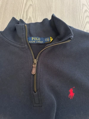 Mörkblå half-zip tröja Polo Ralph Lauren - Mörkblå långärmad tröja från Polo Ralph Lauren med half-zip och ståkrage. I storlek S.