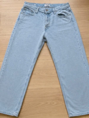  Loose fit jeans - Ljusblå jeans från Jack & Jones i loose fit-modell. Klassisk femficksdesign med dragkedja och knapp. Tillverkade i denim med avslappnad passform och raka ben. Perfekta för en chill och avslappnad stil. Har några snöfläckar men knappast märkbara!