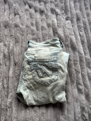 Ljusblå jeans med broderad bakficka - Säljer ett par ljusblå jeans med en snygg broderad W-detalj på bakfickan. 