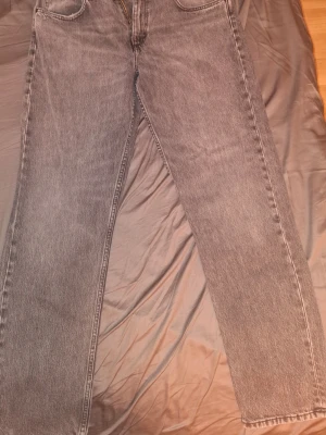Grå raka jeans med hög midja W32 L32 - Ett par grå jeans med rak passform och hög midja. Jeansen har klassiska fem fickor och är tillverkade i denim. Perfekta för en avslappnad och trendig look. Har använt dem ganska mycket men finns mycket liv kvar i dem 