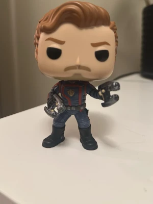 Star-Lord Funko Pop #1201 (Marvel) - Säljer en supercool Star-Lord Funko Pop (#1201) från Guardians of the Galaxy vol 3! Det är en så kallad bobble-head (huvudet sitter på en fjäder).Figuren är i fint skick, men har ett litet skrapmärke på hakan (se sista bilden). Kartongen finns tyvärr inte kvar, säljs löst.Fraktas varsamt! Sökord: Funko pop, Marvel, Star Lord, GotG, samlarfigur, figur, leksak, Avengers.