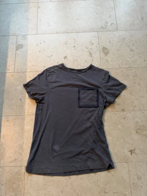 Limitato t-shirt  - Snygg mörkblå t-shirt med korta ärmar och en bröstficka framtill. På ryggen finns ett stort tryck med poolmotiv. Perfekt för en avslappnad och cool stil.