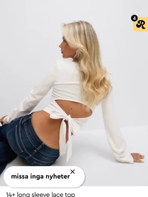Vit långärmad topp med öppen rygg - Trendig vit långärmad topp med öppen rygg och knytband bak. Toppen har en smickrande passform och är perfekt för dig som vill ha en stilren men ändå unik look. Tillverkad i mjukt material som känns skönt mot huden.
