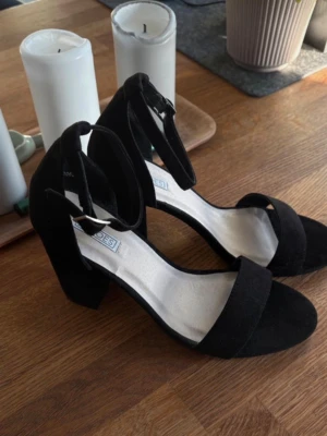  Chunky klackpumps i krossat sammet - Snygga svarta pumps med bred klack och öppen tå. Skorna har en justerbar ankelrem med silverfärgat spänne och är tillverkade i krossat sammet. Enbart testade.