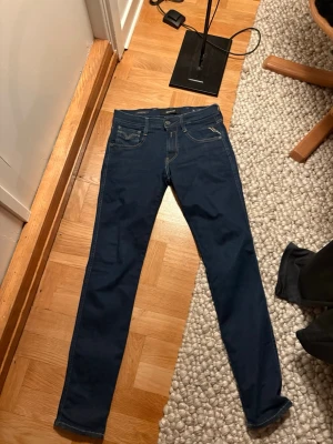 Mörkblå slim fit jeans - Säljer ett par snygga replay jeans som bara ör använda några få gångar. Inga defekter eller fläckar. En liten tråd stickar ut 2cm från fabrik men bara att klippa av om man skulle störa sig på det men absolut inget som syns då jag letade igenom hela byxan efter skador och liknanden. Storlek w28 L30.
