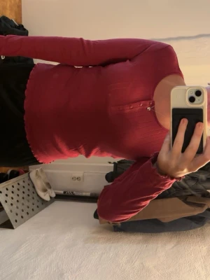Vinröd ribbad långärmad topp Firefly - Säljer en vinröd ribbad långärmad topp från Firefly i storlek M. Toppen har knappar framtill vid halsen och är figurnära med mjukt, stretchigt material. Perfekt att styla med jeans eller kjol för en snygg look.