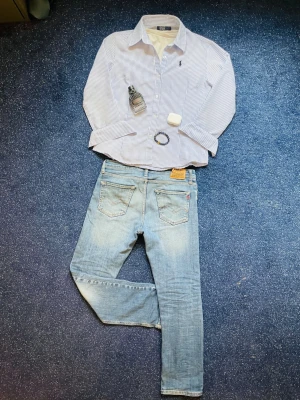 Blårandig linne skjorta från Ralph Lauren - Klassisk linne skjorta från Ralph Lauren med smala blå och vita ränder. Skjortan har lång ärm, knappar framtill och en broderad logga på bröstet. Perfekt till jeans eller chinos för en clean, stilren, Grisch och laidback look. Skjortan passar som unisex. Hör av dig frågor! 