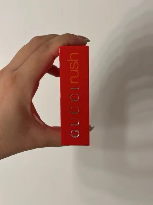Gucci Rush parfym röd - Gucci Rush parfym i en ikonisk, rektangulär röd plastflaska med modern design. Flaskan har tydlig logga på sidan och en minimalistisk look som sticker ut i badrumshyllan. Perfekt för dig som gillar exklusiva och trendiga dofter.