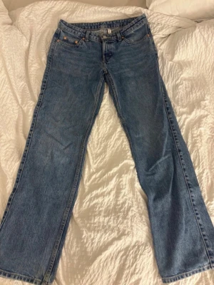 Blå raka jeans - Klassiska blå jeans i rak modell med fem fickor och bälteshällor. Jeansen har en knappgylf och detaljer i kopparfärg. Tillverkade i slitstark denim som ger en tidlös look. Perfekta för dig som gillar enkel och clean stil. Skulle passa en xs också! 