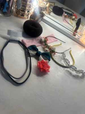 Mix av håraccessoarer med blommor - Säljer ett kit med håraccessoarer: svart hårdonut, rosa hårband med broderi och blommor, blåvit rosett, hårspänne med rosa blomma, svart diadem med vita blommor, gult diadem med pärlor och ett silvrigt diadem med lövmönster. Perfekt för dig som vill variera din stil.