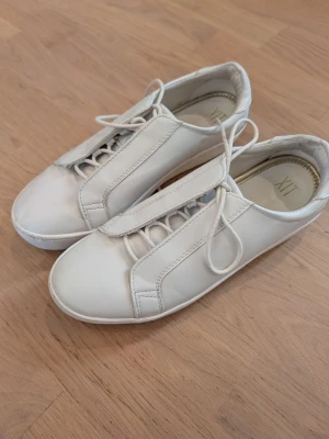 Vita sneakers med platå - Stilrena vita sneakers med klassisk snörning. Skorna har en clean design utan synliga loggor med platå. Perfekta för dig som gillar en enkel och modern look. 