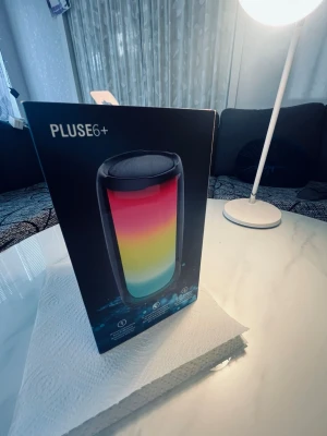 Pluse6+ bärbar högtalare med LED-ljus - Snygg bärbar högtalare, modell Pluse6+, med färgglada LED-ljus som lyser i flera nyanser. Högtalaren har en cylinderformad design och svart ram. Perfekt för att ta med sig och spela musik trådlöst. Materialet är plast och högtalaren har en modern look.