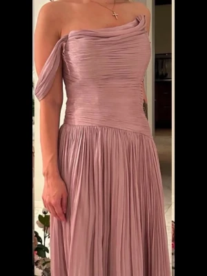 Klänning - Elegant mauve långklänning med offshoulder-design och draperad överdel. Klänningen har snörning i ryggen för justerbar passform, passar storlek 36-40. Pris går att diskutera 