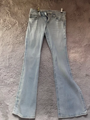 Ljusblå bootcut jeans från Gina Tricot  - Säljer ett par ljusblå bootcut jeans från Gina Tricot med klassisk femficksdesign och låg midja. Jeansen har utsvängda ben och är tillverkade i mjukt denimtyg som ger en avslappnad look. Perfekta för dig som gillar retrovibbar och vill ha ett par riktigt snygga jeans. Storlek 38
