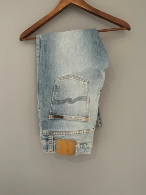 Ljusblå jeans från Nudie Jeans - Säljer ett par ljusblå jeans från Nudie Jeans modellen lean dean en riktig trendig modell. Modellen på bilden är ca 175. Storlek 30 30. Men jeansen är lite lätt uppsydda. Hör av er vid minsta funderingar!
