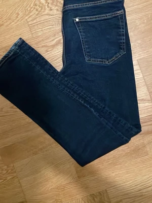 Mörkblå H&m jeans - Snygga mörkblå skinny jeans med klassisk femficksdesign och kontrastsömmar. Jeansen har en smal passform och är tillverkade i stretchigt denimtyg för extra komfort. Perfekta för en trendig och avslappnad stil.
