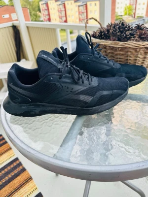 Svarta Reebok sneakers i mesh - Snygga helsvarta sneakers från Reebok med låg profil. Skorna har ovandel i mesh och syntetmaterial, samt klassiska snörningar. Perfekta för dig som gillar en clean och sportig look.