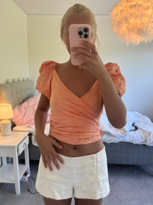 Orange topp - Orange topp med band som man får skjustera hur många varv runt midjan man vill ha alltså hur kort den ska vara. Som längst kan den vara som den är på bilden skulle jag säga. Man kan även välja hur långa armarna ska vara som ni kan se på de två sista bilderna 