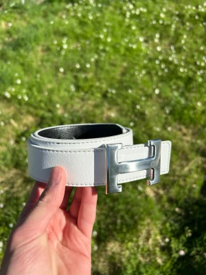 H bälte vit/silver - Tja säljer nu ett helt nytt bälte som är riktigt snyggt, om man vill kan man vända på det så kan man ha den svarta, 115cm.                                            Hör av er vid frågor!