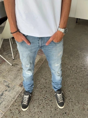Ljusblå slitna slim fit jeans från replay - Säljer ett par ljusblå slim fit jeans med slitningar och lätt tvättad look. Jeansen har klassisk femficksmodell och normal midja. Perfekta för en avslappnad och trendig stil. W30 L34