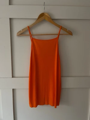 Orange linnetopp från Massimo dutti  - Snygg orange linnetopp med tunna axelband och rak passform. Perfekt för varma dagar och enkel att matcha med jeans eller kjol. Toppens material känns lätt och luftigt.