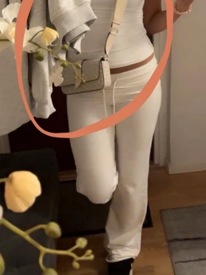 Beige Michael Kors handväska - Snygg beige handväska från Michael Kors med guldigt MK-emblem på framsidan. Väskan har ett diskret mönster och justerbar axelrem i ljust material. Perfekt storlek för det viktigaste och ger en clean look till din outfit.