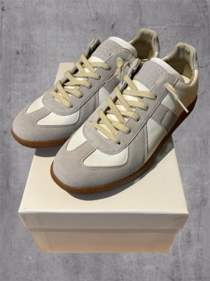 Vita Maison Margiela Gats  - Säljer ett par Maison Margiela GAT som inte kommer till användning längre. Skorna är i nyskick och har endast använts ett fåtal gånger. En väldigt stilren och tidlös modell som fungerar till i princip allt. Säljs då jag rensar garderoben. Hör gärna av dig om du har några frågor eller vill ha fler bilder.  Kvitto finns!