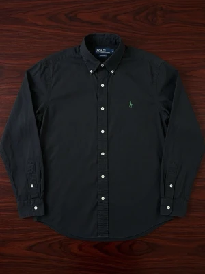 Svart skjorta från Polo Ralph Lauren - Klassisk svart skjorta från Polo Ralph Lauren med button-down krage och vita knappar. Broderad grön logga på bröstet. Skjortan har lång ärm och är tillverkad i bomull för en skön känsla. Perfekt till en clean och stilren look.
