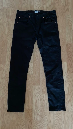 Svarta jeans Lager 157 - Ett par svarta jeans från Lager 157 i storlek L. Klassisk rak passform med knapp och dragkedja i midjan. Jeansen är tillverkade i ett mjukt och stretchigt material som gör dem bekväma att bära hela dagen.