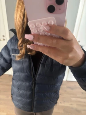 Mörkblå pufferjacka ifrån Peak Performance - Snygg mörkblå pufferjacka från Peak Performance med hög krage och dragkedja framtill. Jackan har två sidofickor med dragkedja.Perfekt för kalla vinterdagar och riktigt skön att bära.DEN HAR ETT LITET HÅL PÅ ARMEN, man kan se de på bilderna👍👍👍