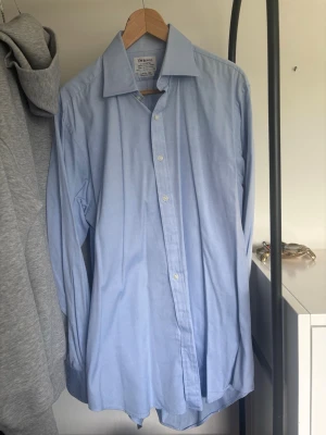 Ljusblå klassisk skjorta - Säljer en ljusblå skjorta. Skjortan har lång ärm och är tillverkad i bomull, perfekt för en clean och stilren look. Passar till både jeans och kostymbyxor. Ny pris 1000