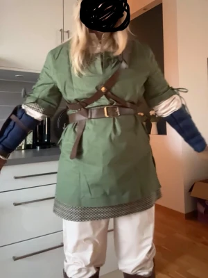 The Legend of Zelda: Twilight Princess Link Cosplay – XL + Boots - Complete costume including green tunic, green hat, white pants, white undershirt chainmail-style undershirt/hem, belt + harness, 2 pouches, blue arm sleeves, gloves, arm guard and brown boots. Boots are approx. 25 cm insole & 43 cm calf circumference. Costume size: approx. 175–180 cm height, 110–114 cm chest, 88–93 cm waist & 114–119 cm hips. Costume is has never been worn aside form a initial fitting!  Feel free to ask me any questions!