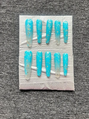 Blå Press-on naglar || Storlek S - Snygga press-on naglar i en cool blå färg med transparent bas och detaljer av guldglitter. Storlek S. Naglarna har en lång, smal kistform (coffin shape) som ger en trendig look. Perfekt för dig som vill ha något extra till naglarna utan att behöva gå till salong. Naglarna kommer även med ett armband som matchar. Det du får med dig också: * Fil och manikyr pinne * nagellim klistermärken * 2 lappar av rengöring för naglar.